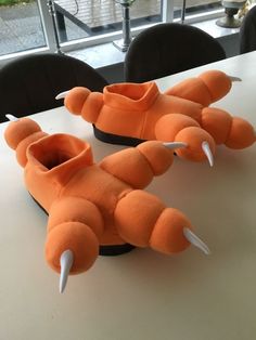 an orange stuffed animal sitting on top of a white table next to black chairs and windows