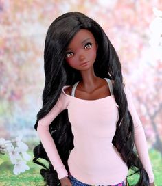 a doll with long black hair standing in front of a flowered wall and grass