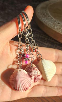 a person is holding two seashells in their hand and one has a pink bead on it