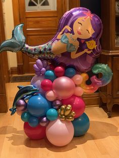 the balloon mermaid is sitting on top of balloons