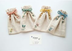 three small bags with ties tied to them on top of a white table next to a business card