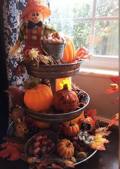 a three tiered tray filled with pumpkins, gourds and other decorations