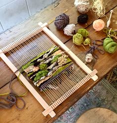 several balls of yarn sitting on top of a table next to a weaving loom