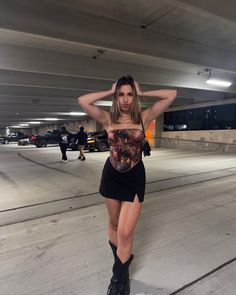 a woman is standing in an empty parking garage with her hands on her head and looking at the camera