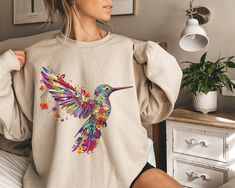 "Hummingbird Sweatshirt, Gift For Her, Spring Birds, Bird Sweatshirt, Bird Lover Gift, Watercolor Hummingbird, Floral Hummingbird Shirt Matching T-Shirt: https://www.etsy.com/PrintWorkShopCompany/listing/1504229365/floral-hummingbird-shirt-animal-lover?utm_source=Copy&utm_medium=ListingManager&utm_campaign=Share&utm_term=so.lmsm&share_time=1688570829048 ** HOW TO ORDER 1. Check our photos for sizing and color options.  2. Select your size and color from the drop-down menus.  3. Click \"ADD TO CA Nature Inspired Fashion, Spring Wardrobe Essentials, Watercolor Hummingbird, New York Sweatshirt, Floral Sweatshirt, Holiday Hoodies, Design Sweatshirt, Sweatshirt Graphic, California Girl