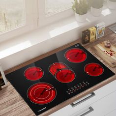 an electric stove top with four burners in the middle and red lights on it