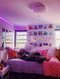 a person laying on a bed in a room with purple lighting and pictures on the wall