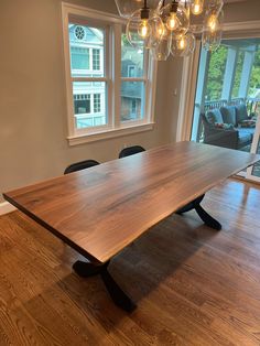 a large wooden table sitting in the middle of a living room next to a window