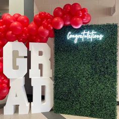 the entrance to an office decorated with red balloons and greenery, along with large letters that spell out congratulations