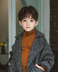 a young boy wearing a coat and turtle neck sweater