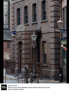 an old brick building with many windows on the front and side, along with a lamp post