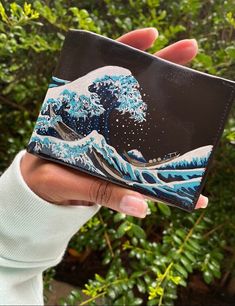 "Hand painted mens wallet using leather acrylic paint and sealed with a water & dust resistant top coat. The great wave off Kanagawa AKA the Japanese wave is handpainted on this custom Perry Ellis leather wallet for men. FEATURES AND DETAILS OF WALLET Exterior: Genuine Leather, Lining: Polyester Imported Fashion with functionality: classic passcase wallet made with leather. includes 6 credit card slots and roomy single currency pocket to provide maximum storage space. comes with one multi-functi Painting On Leather Wallet, Japanese Wave, The Great Wave, Japanese Waves, Great Wave Off Kanagawa, Wallet For Men, Leather Paint, Mens Wallet, Groomsmen Gift