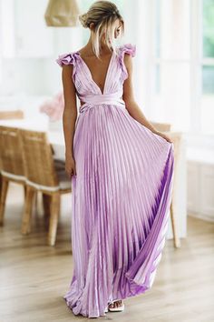 a woman in a purple dress standing on a wooden floor with her back to the camera