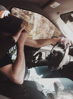 a man sitting in the driver's seat of a car with his hands on the steering wheel