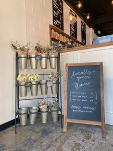 a chalk board with flowers on it next to a shelf filled with pots and pans