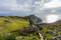 a man standing on top of a lush green hillside