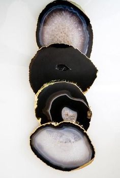 three pieces of black and white agate shell on a white surface with one piece cut in half