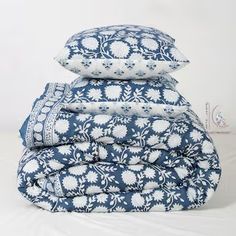 three pillows stacked on top of each other in blue and white colors with floral designs