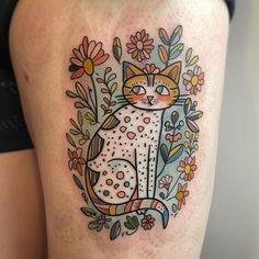 a woman's thigh with a cat and flowers tattoo design on the side of her leg