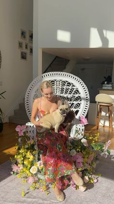 a woman sitting in a chair with a dog on her lap and flowers around her