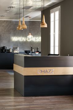 the front desk of a restaurant with lights hanging from it's ceiling and wood flooring