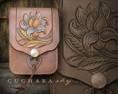 two leather bags with designs on them sitting next to each other in front of a wooden wall