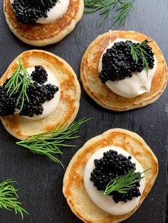 four pancakes with black cauliflower and cream on top, sitting on a slate board