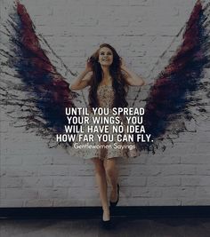 a woman standing in front of a brick wall with an angel wings quote on it