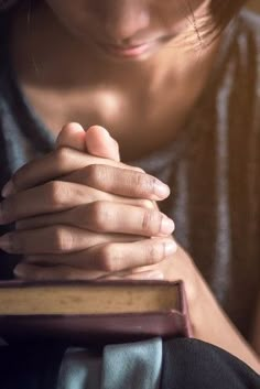 a woman is holding her hands together and praying