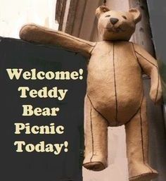 a teddy bear hanging from the side of a building with a sign that says welcome teddy bear picnic today