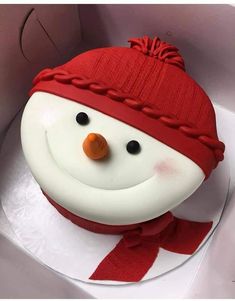 a snowman cake with red and white frosting on it's face in a box