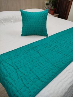 a bed with two pillows on it and a green blanket draped over the headboard