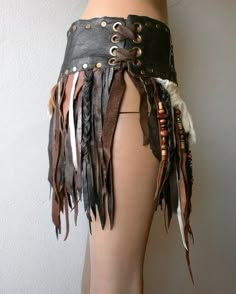 a woman's skirt made out of leather with feathers and chains on the bottom