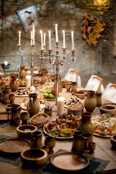 a table with many plates and candles on it