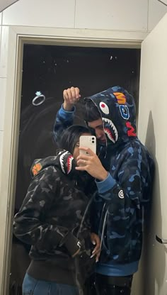 two people taking a selfie in front of a mirror with shark masks on their faces