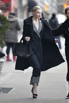 two women are walking down the street with one carrying a handbag and another holding a purse