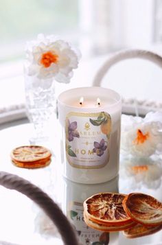 a white candle sitting on top of a table next to some orange slices and flowers