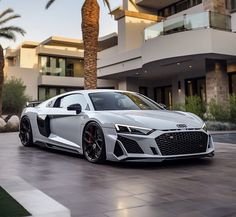 a white sports car parked in front of a large building with palm trees on the side