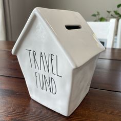 a white ceramic box with the words travel fund written on it sitting on a wooden table