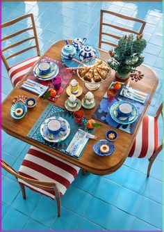 a wooden table topped with plates and cups