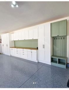 an empty garage with white cabinets and drawers