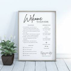 a welcome sign is next to a potted plant on a wooden floor in front of a white wall