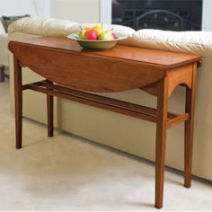 a bowl of fruit sitting on top of a wooden table next to a white couch