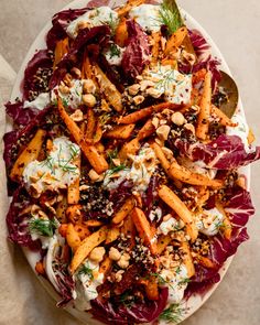 a salad with carrots, lettuce and other toppings on a white plate