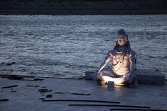 a statue sitting on the ground next to water