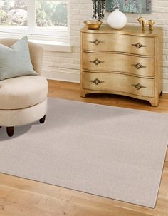 a living room area with a chair, dresser and rug on the hardwood flooring