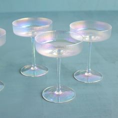 four empty wine glasses sitting next to each other on top of a blue tablecloth