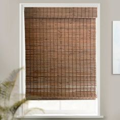 a bamboo blind hanging on the side of a window in front of a white wall