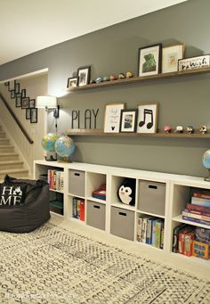 a living room filled with lots of furniture and bookshelves next to a stair case