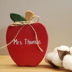 a red apple sitting on top of a wooden table next to a white cotton ball